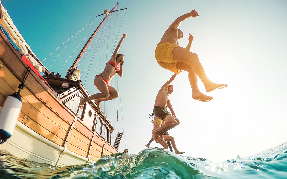 Fr&uuml;hbucher Angebote: Freunde springen vom Boot aus ins Meer