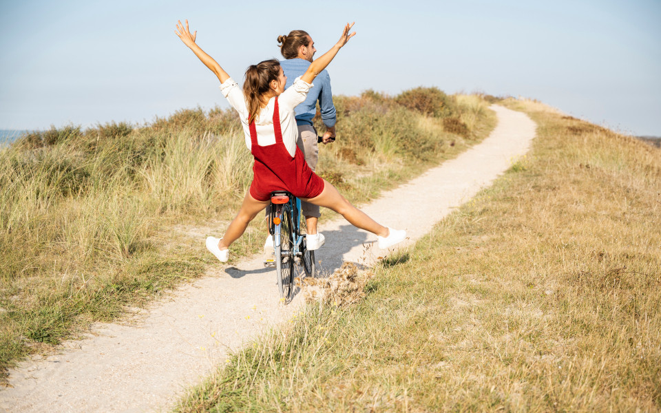 Unbeschwerte Freundin genie&szlig;t Fahrradtour mit Freund an einem sonnigen Tag