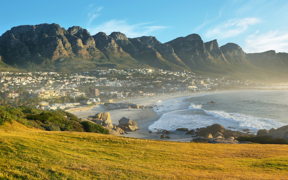 Camps-Bay-Strand in Kapstadt bei Sonnenuntergang, Südafrika, mit den „Twelve Apostles“ im Hintergrund.
